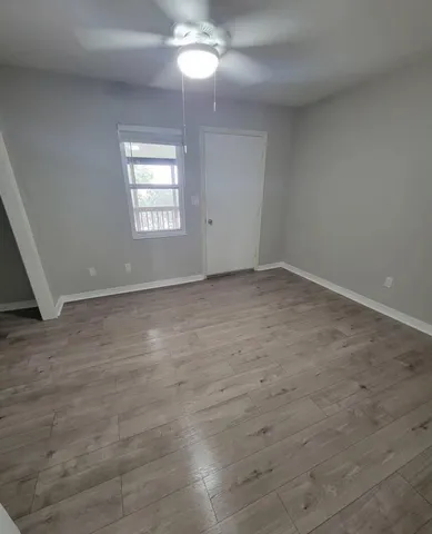 an empty room with windows and ceiling fan