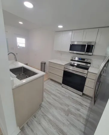 a kitchen with stainless steel appliances a stove a microwave a sink and white cabinets