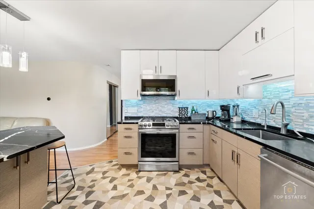 a kitchen with stainless steel appliances granite countertop a stove a sink and a microwave