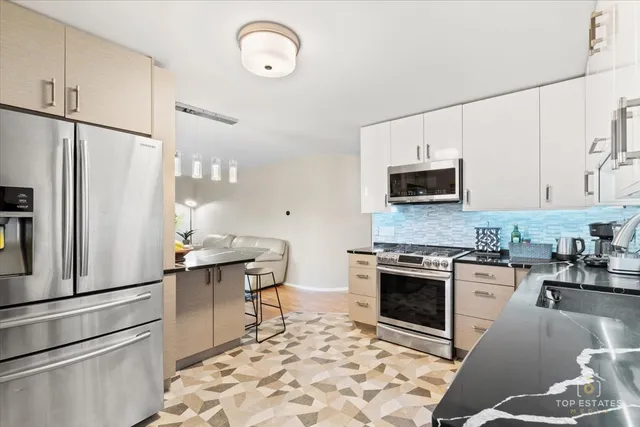 a kitchen with stainless steel appliances granite countertop a stove a sink and a refrigerator