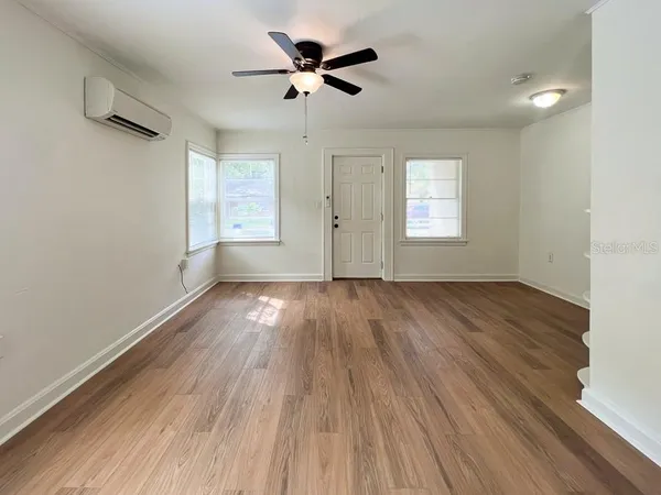 an empty room with wooden floor and windows