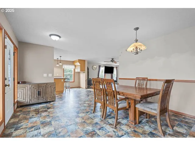 a view of a dining room and livingroom with furniture wooden floor a rug a fireplace and a chandelier