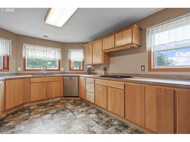 a kitchen with granite countertop a sink window and cabinets