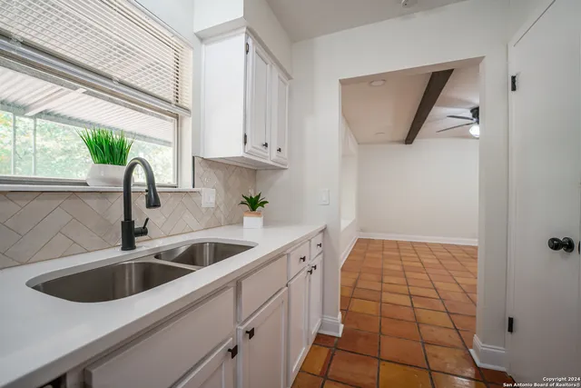 a view of an empty room with a window and a kitchen