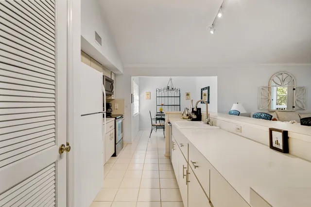 a large white kitchen with a lot of counter space and a refrigerator