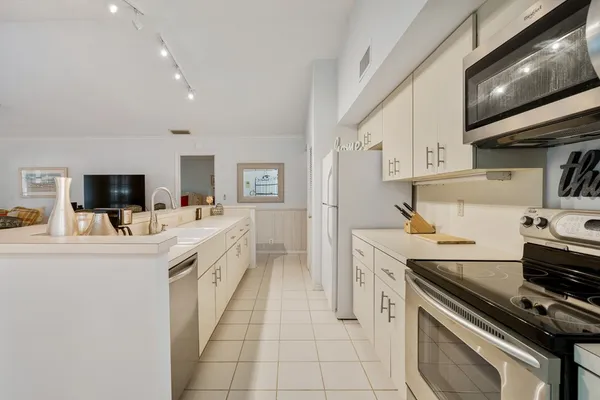 a kitchen with stainless steel appliances a white stove top oven a sink dishwasher and a refrigerator with the cabinets