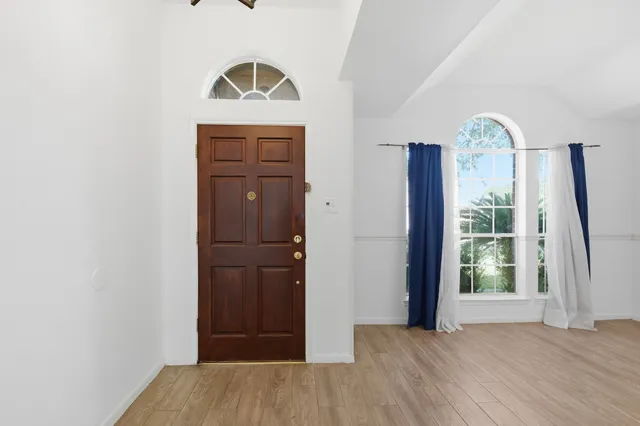 an empty room with wooden floor mirror and entrance