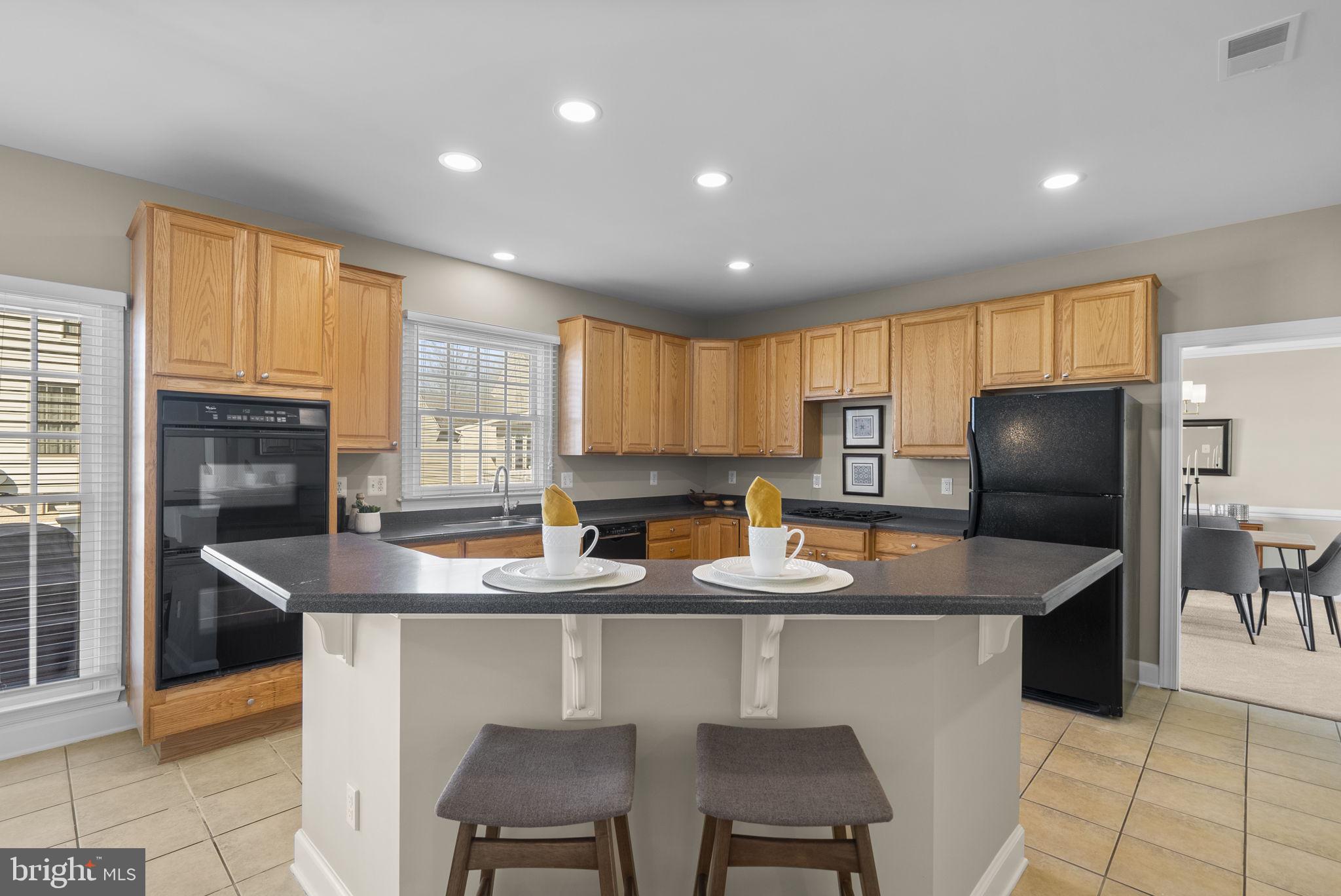 14421 Ashleigh Greene Road Boyds, MD 20841 - Photo 20 of 95 a kitchen with stainless steel appliances granite countertop a sink a stove a refrigerator cabinets and a dining table with wooden floor
