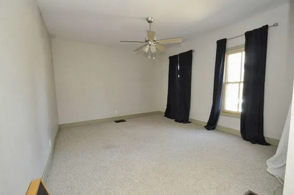 an empty room with closet and a chandelier fan