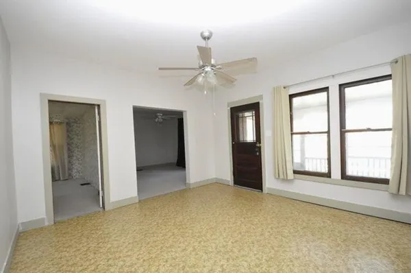 an empty room with windows and ceiling fan