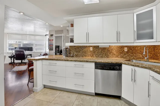 a kitchen with white cabinets and sink