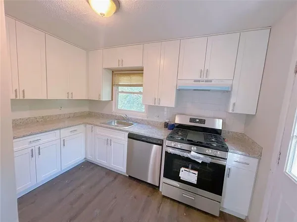 a kitchen with granite countertop white cabinets and appliances