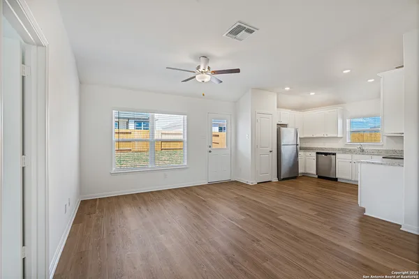 a view of an empty room with a window and wooden floor