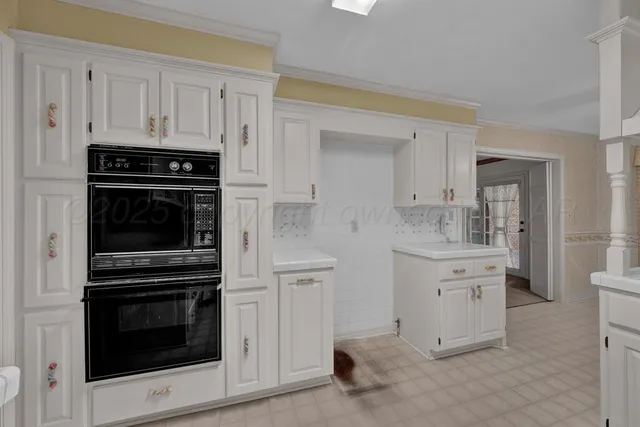 a kitchen with white cabinets and appliances