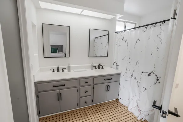 a bathroom with a double vanity sink mirror and shower
