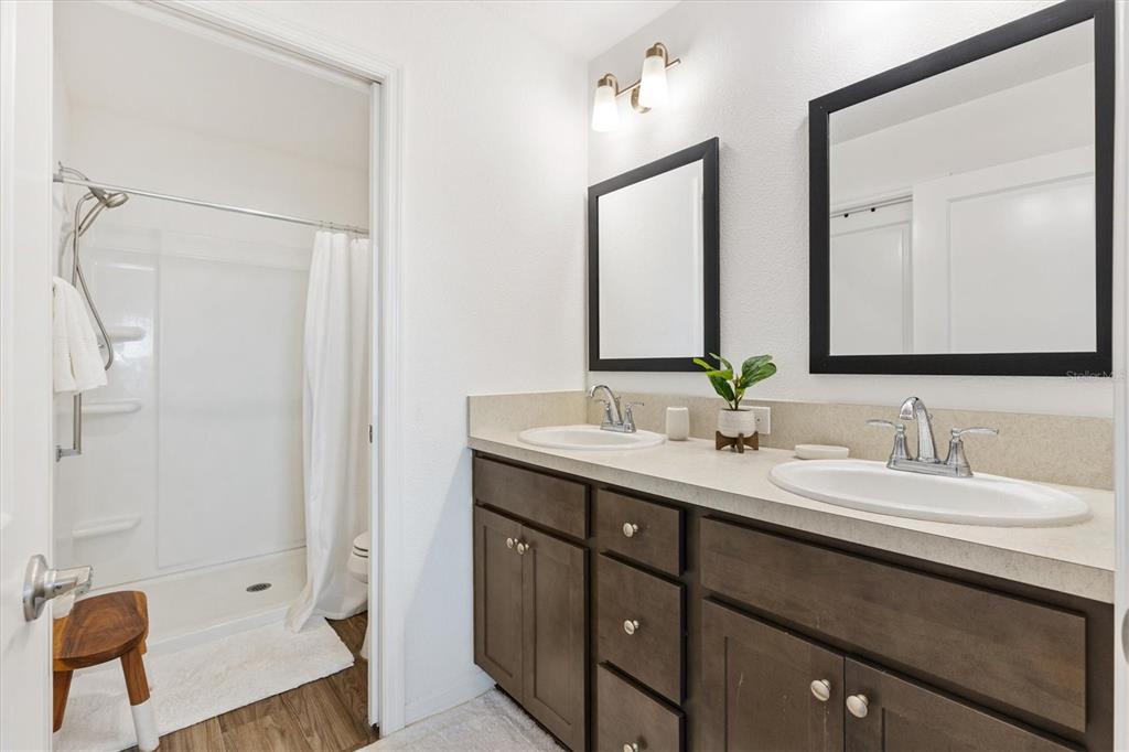 6767 Mary Loop The Villages, FL 34762 - Photo 12 of 26 a en suite bathroom with a double vanity sink a large mirror and shower