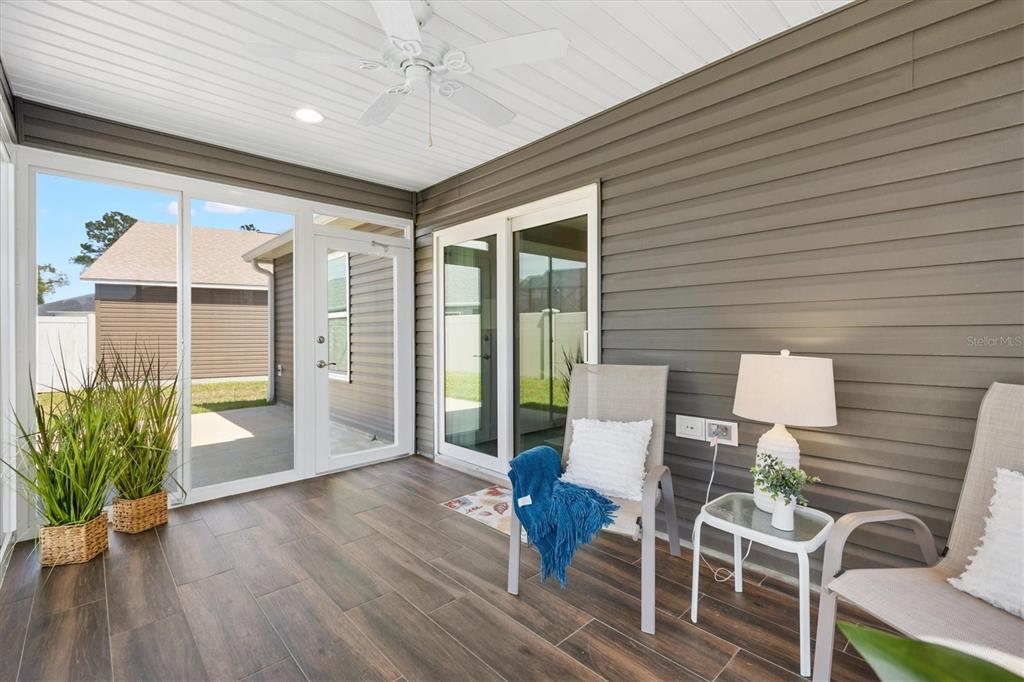 6767 Mary Loop The Villages, FL 34762 - Photo 20 of 26 a view of a patio with table and chairs potted plants with wooden floor and fence