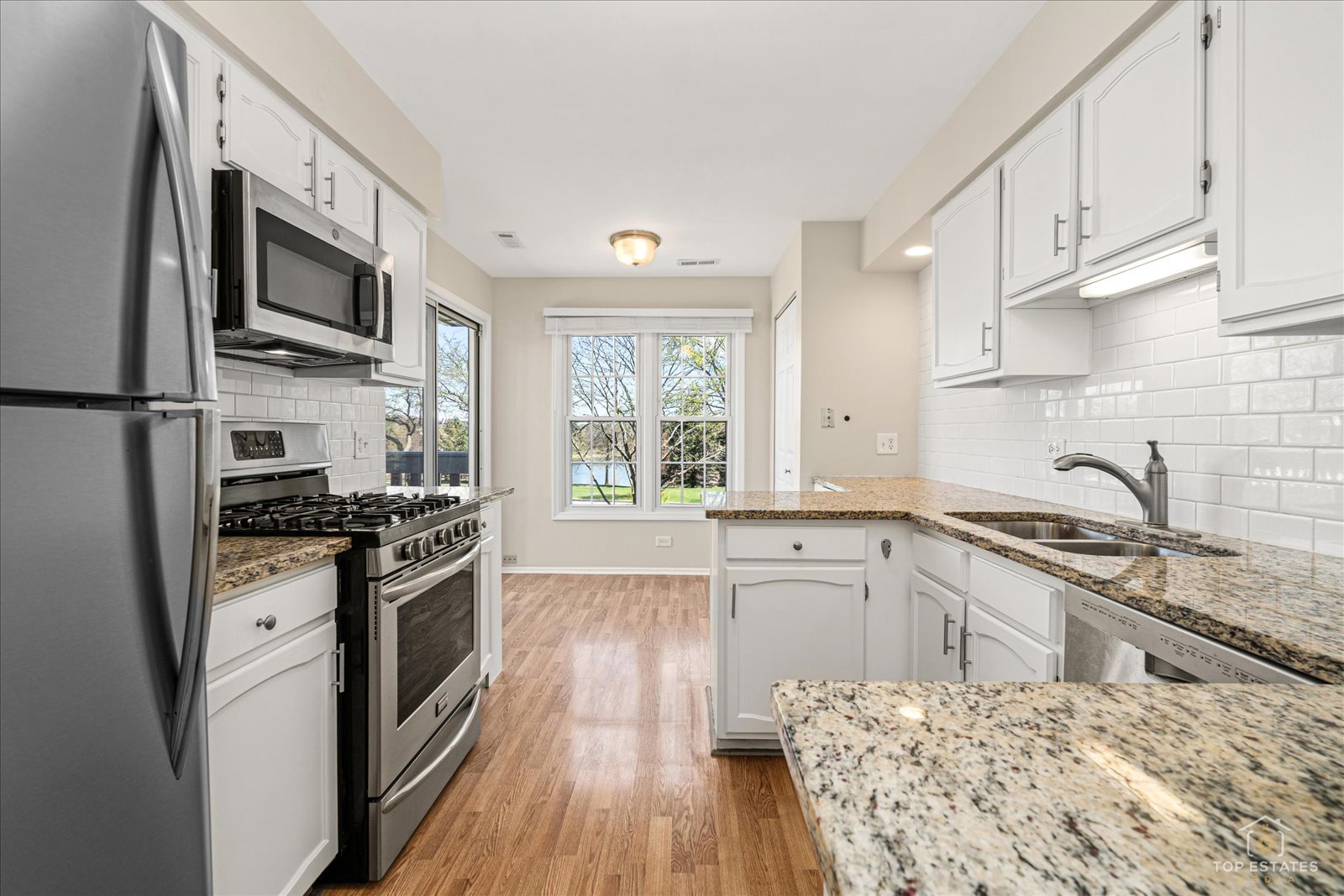 1427 Sutton Court, Unit 1427 Vernon Hills, IL 60061 - Photo 9 of 27 a kitchen with stainless steel appliances granite countertop a stove top oven a sink dishwasher a refrigerator and cabinets with wooden floor