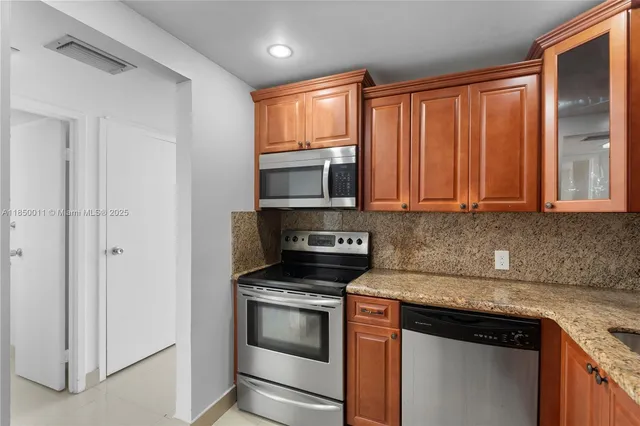 a kitchen with granite countertop wooden cabinets and stainless steel appliances