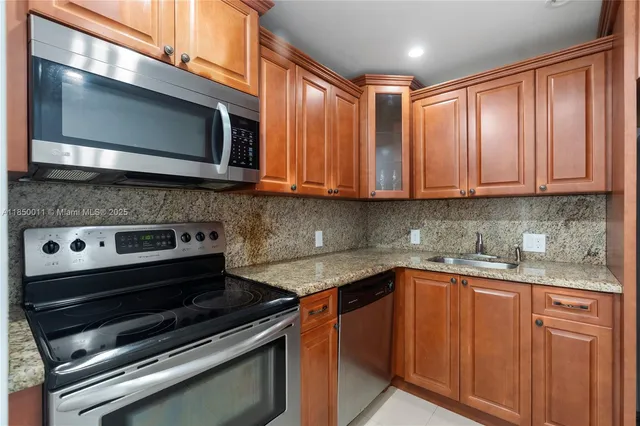 a kitchen with stainless steel appliances granite countertop a stove microwave and sink