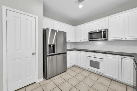 a large kitchen with granite countertop a sink window and white cabinets