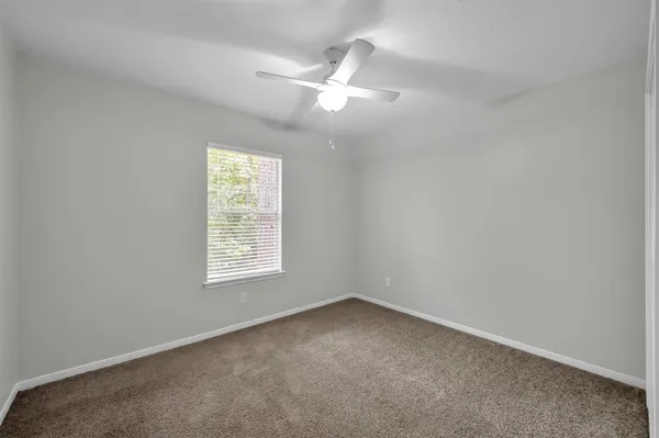 an empty room with a window and a fan