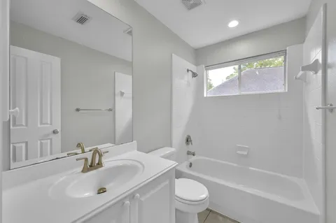 a bathroom with a bathtub shower sink vanity mirror and toilet