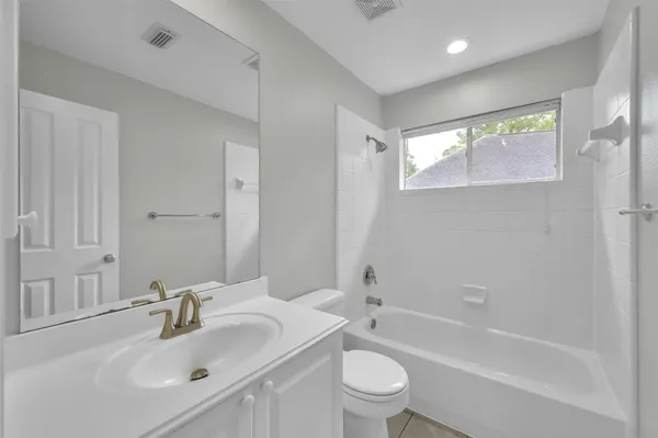 a bathroom with a bathtub shower sink vanity mirror and toilet