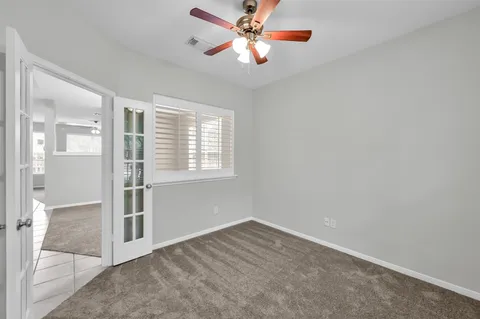 an empty room with chandelier fan and windows