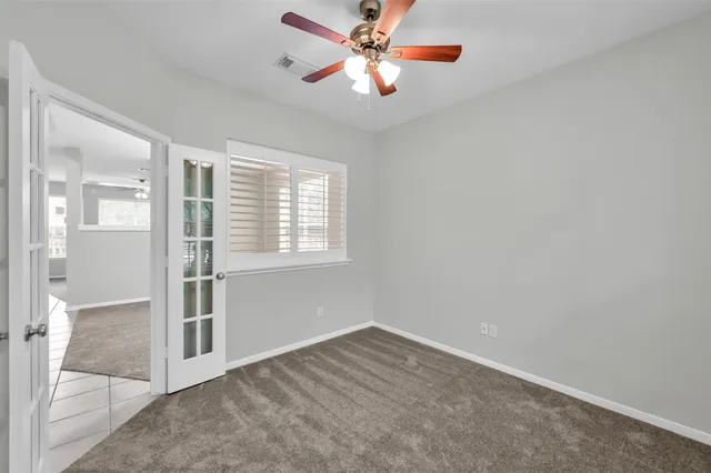 an empty room with chandelier fan and windows