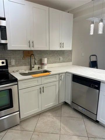 a kitchen with white cabinets and white appliances