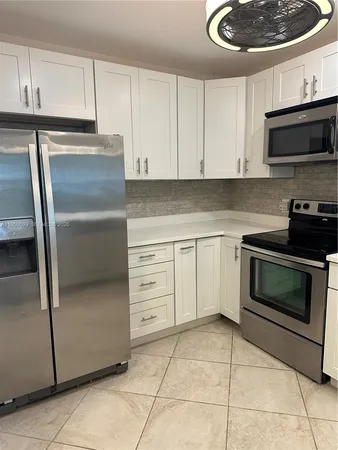 a kitchen with granite countertop white cabinets and stainless steel appliances