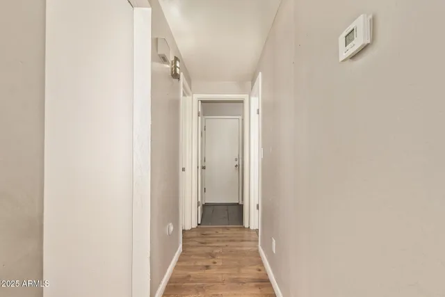 a view of a hallway with wooden floor and a bathroom