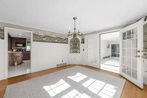 a view of a hallway with wooden floor and a chandelier