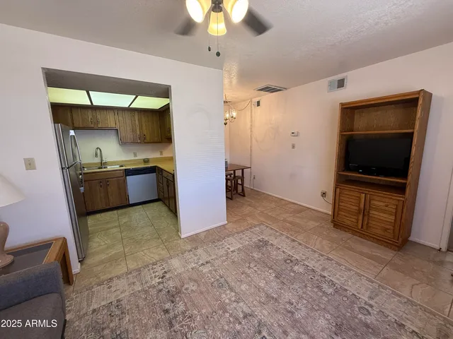 a living room with stainless steel appliances kitchen island granite countertop a rug and a flat screen tv