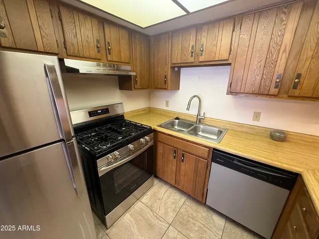 a kitchen with granite countertop cabinets stainless steel appliances and a sink