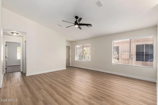 a view of empty room with wooden floor and fan