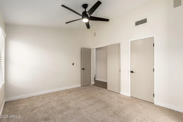 an empty room with windows and fan