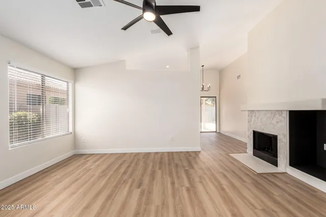 an empty room with wooden floor fireplace and windows