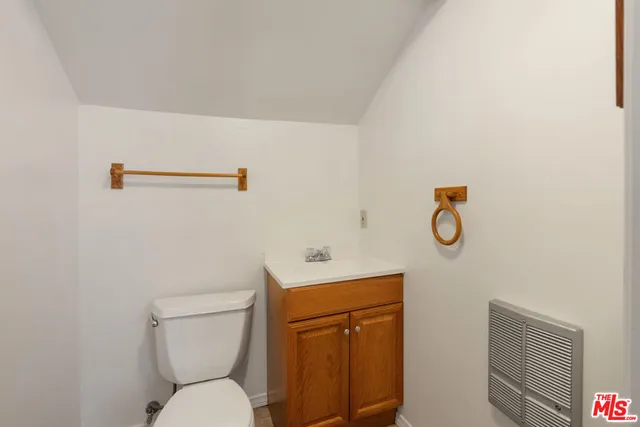 a bathroom with a toilet sink vanity and mirror