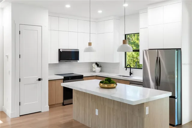 a view of a kitchen with kitchen island a sink stainless steel appliances and cabinets