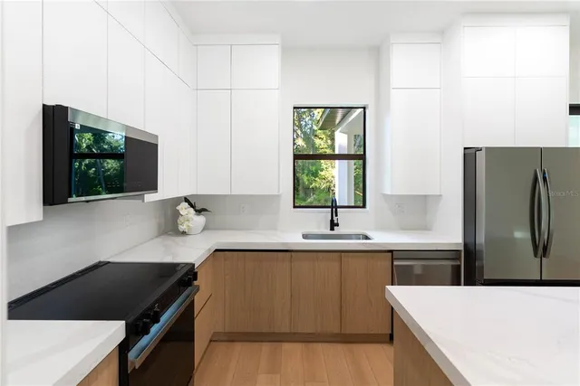 a open kitchen with stainless steel appliances granite countertop a refrigerator a oven a stove and a wooden floors