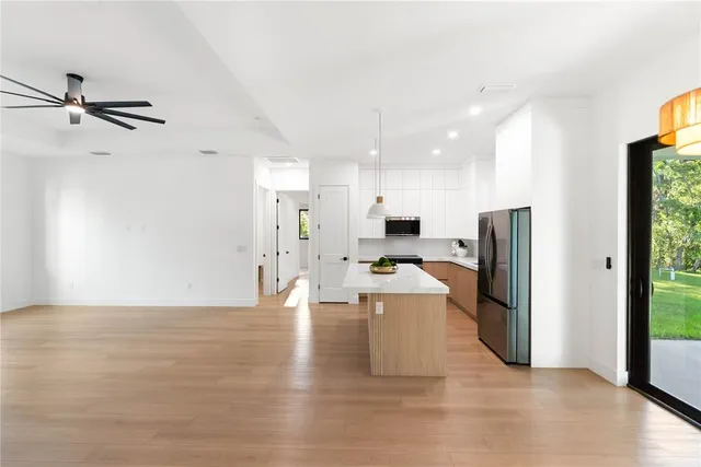 a large kitchen with stainless steel appliances a large counter top a sink a refrigerator and a window