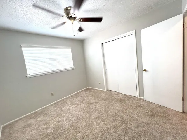 an empty room with windows and fan
