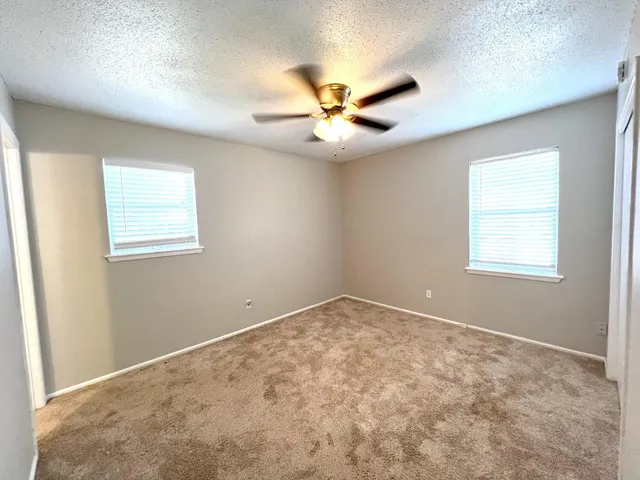 an empty room with windows and fan