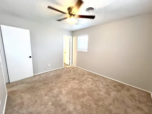 an empty room with a window and a fan