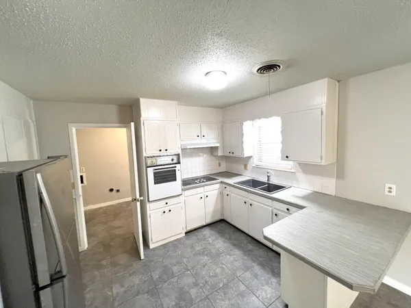 a kitchen with granite countertop a refrigerator stove and sink