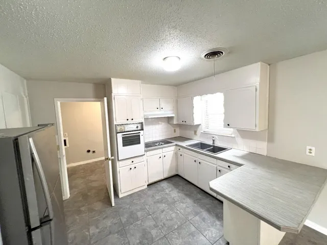 a kitchen with granite countertop a refrigerator stove and sink