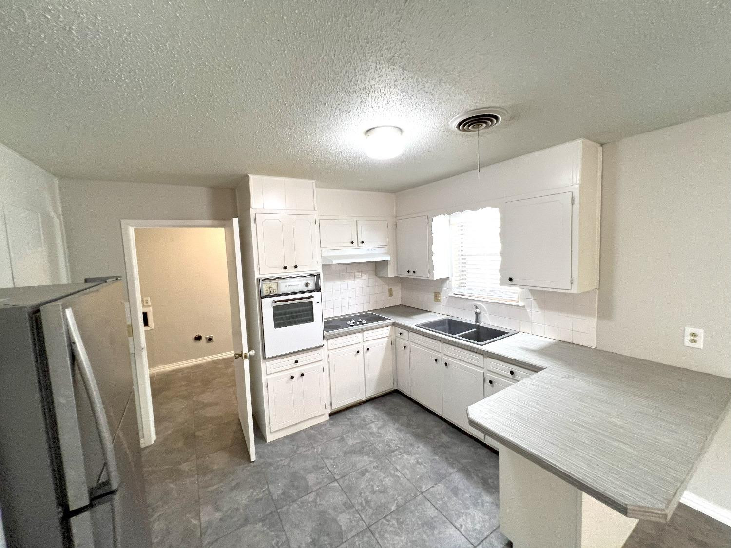 5540 18th Street Lubbock, TX 79416 - Photo 4 of 18 a kitchen with granite countertop a refrigerator stove and sink