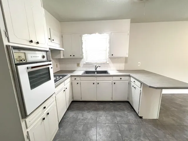 a kitchen with granite countertop white cabinets and white appliances
